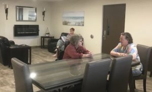 Three members sit at a table and on a couch in a newly renovated common area