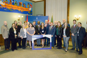 A group of co-op supporters stand together at Queen's Park holding an IncludeCoop frame