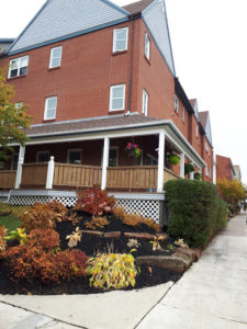 A garden, in front of a low-rise brick building