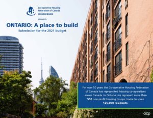 A view of the CN Tower from a leafy street with a rosy brick residential building on one side.