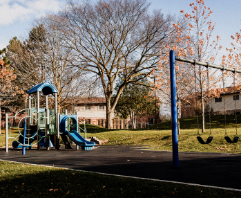 A playground with mature trees and a blue sky overhead