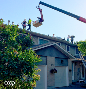 Construction equipment in use on a row of homes, with construction workers on the roof