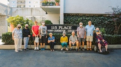 Residents of 115 Place gather around the building's lawn sign.