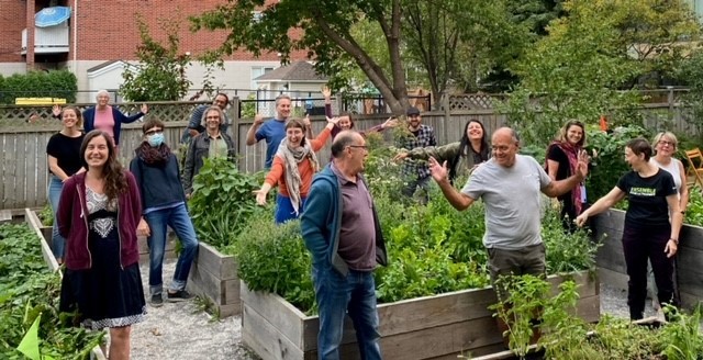 A group of people stand triumphantly around a series of raised garden beds