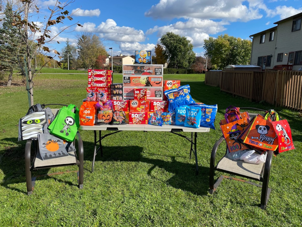 A table sits on the co-op's lawn, piled with Halloween treats