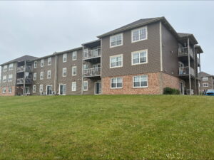 A 3-storey apartment building with balconies surrounded by a lawn.