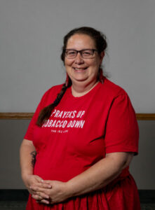 A smiling woman wears an orange t-shirt that says "Prayers up Tobacco down"
