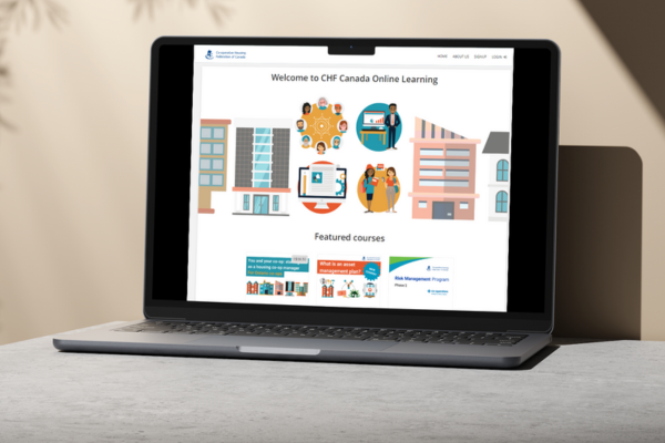 A laptop on a desk displays the CHF Canada Online Learning homepage, showcasing illustrated buildings, people, and featured course sections focused on co-operative housing.